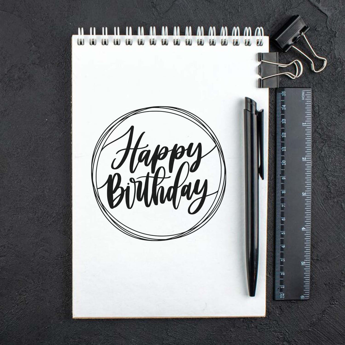 Happy Birthday Circular Framed Lettering Stamp - Premium Vintage Pro Wooden imprint stamped in black ink. Happy Birthday appears in brush script inside several loosely drawn circular outlines.