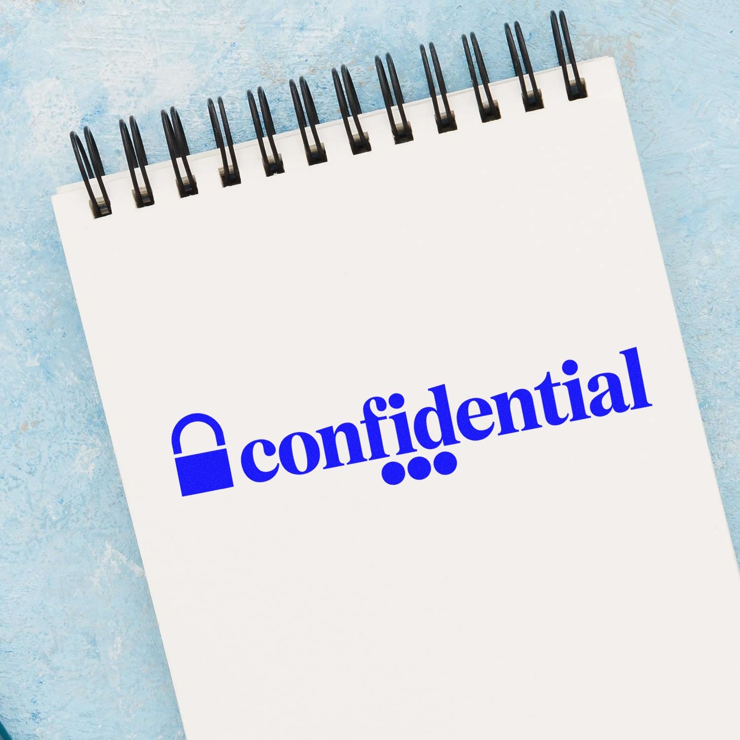 Confidential rubber stamp imprint with lock icon on notebook page for secure office documents and record labeling.