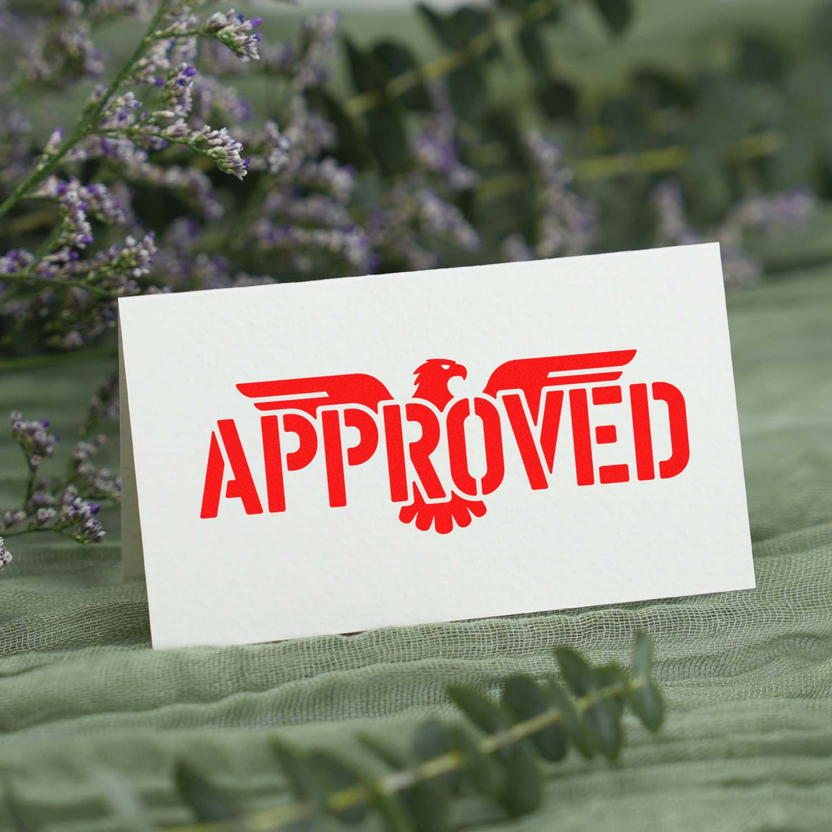 Red Approved rubber stamp with eagle logo on white card, for office approvals and business forms.
