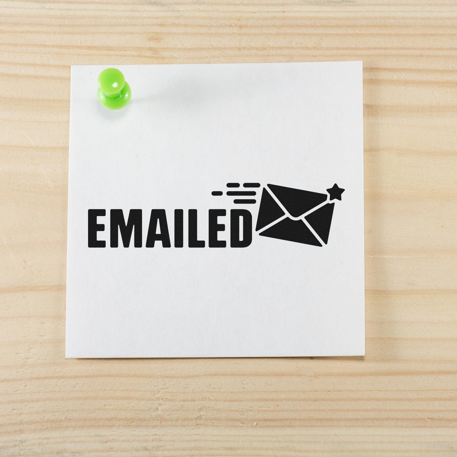 Emailed rubber stamp imprint on white note pinned to wood desk, with envelope icon for office mail tracking.