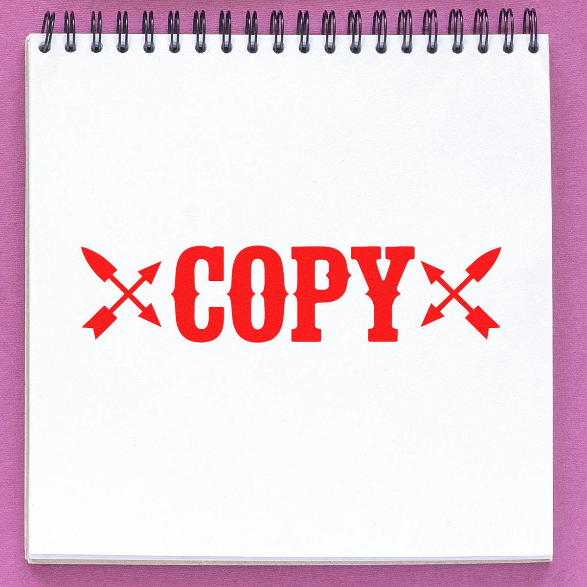 Red COPY rubber stamp with crossed arrows on a blank spiral notebook page