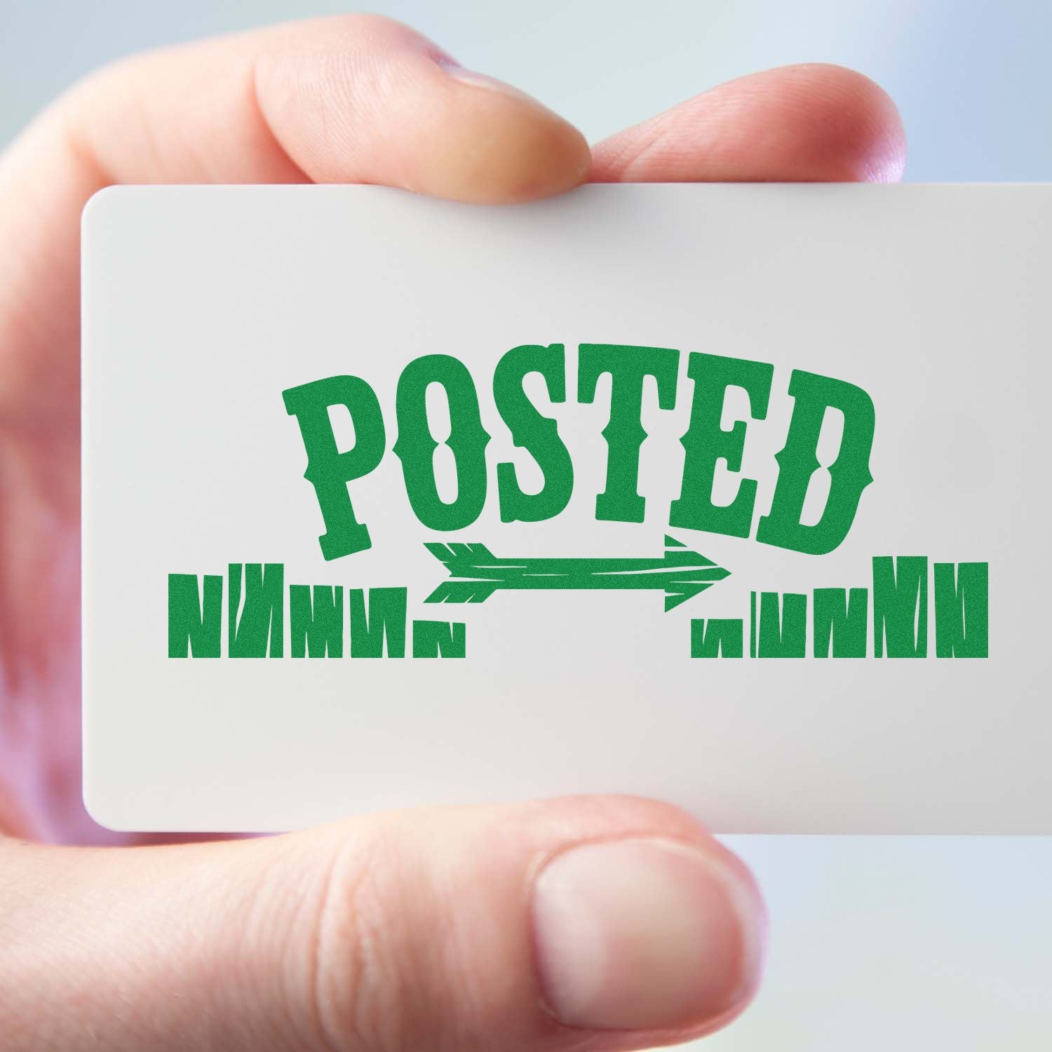 Hand holding card with green POSTED rubber stamp design, ideal for custom business mailing stamps.