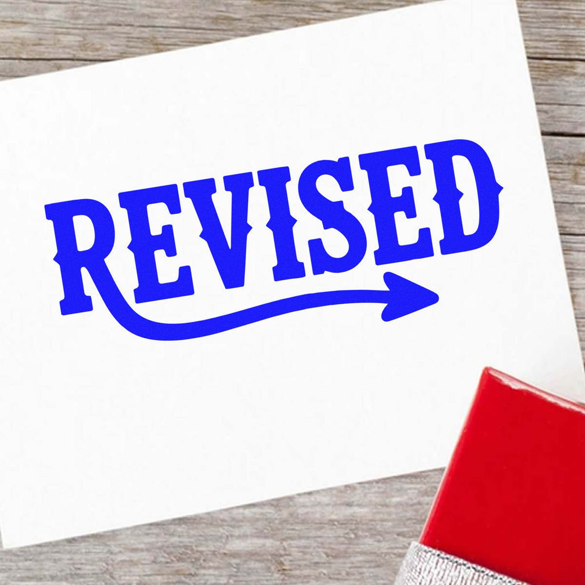 Blue Revised rubber stamp on paper with red stamp handle, ideal for office document review, editing, and approval workflows.