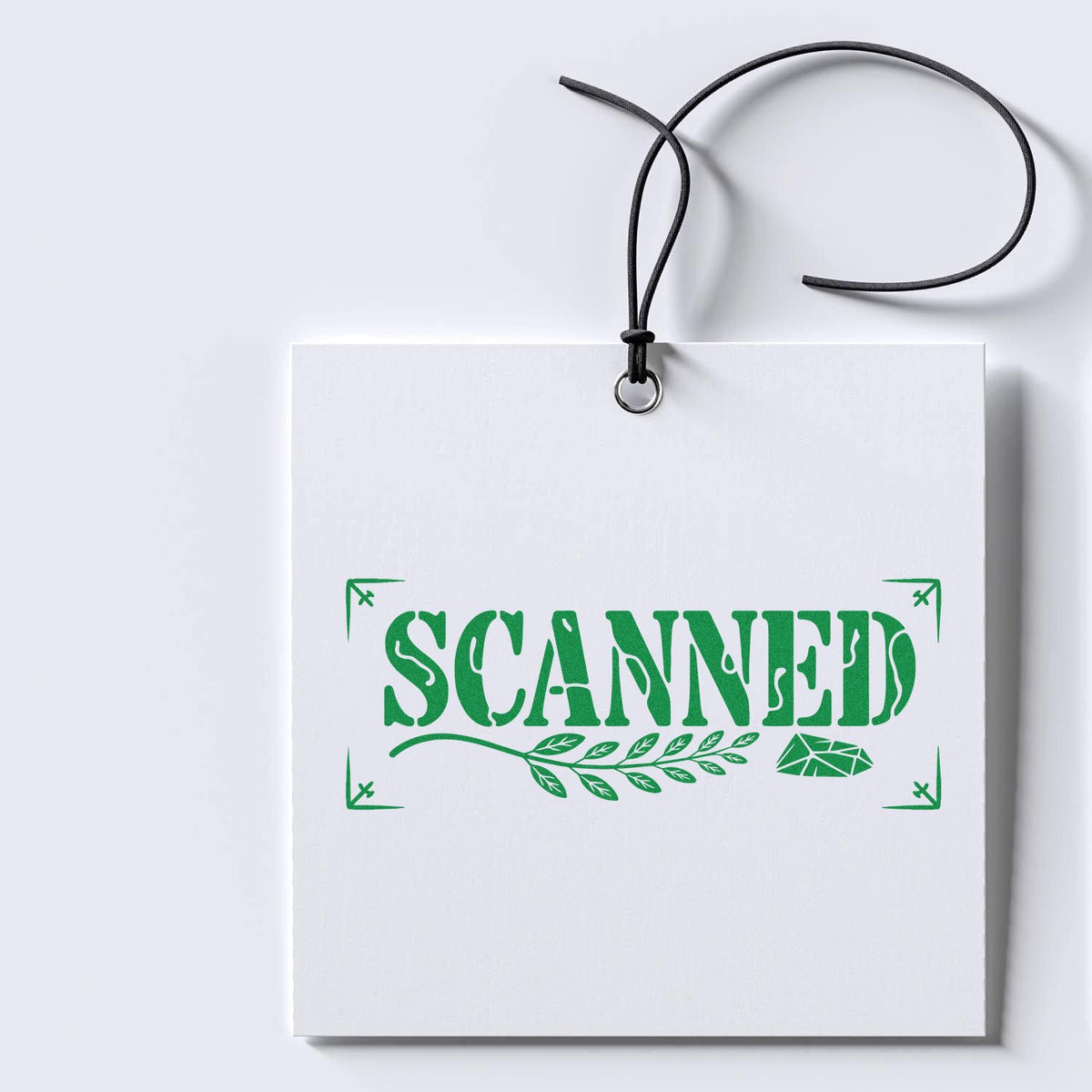 Green SCANNED rubber stamp design on a white hanging tag for document or package marking.