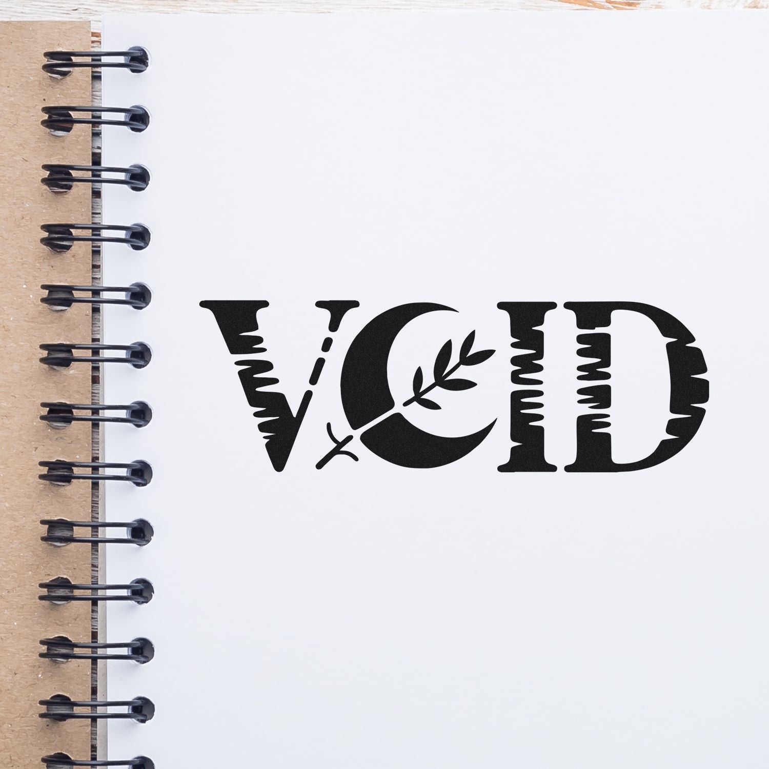 VOID rubber stamp impression on a spiral notebook page, decorative black office stamp for document cancellation or marking.