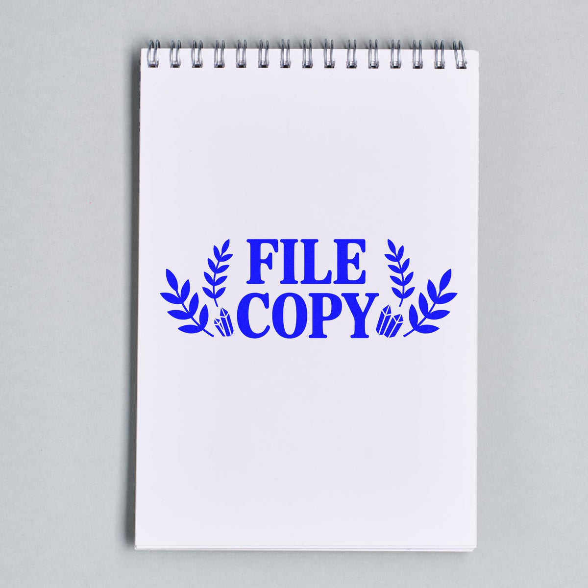 FILE COPY rubber stamp design with decorative leaves stamped on a spiral notebook page for office filing.