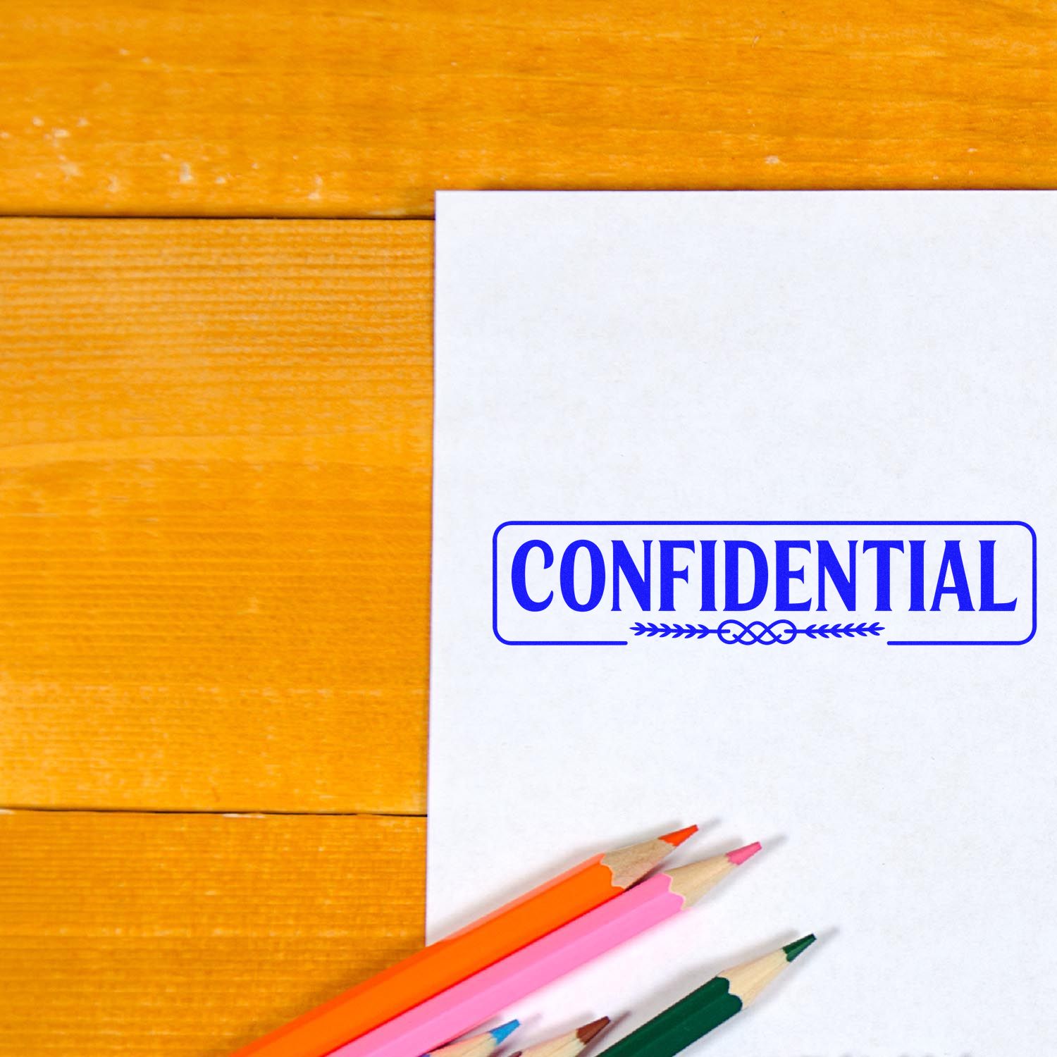 Confidential rubber stamp on paper with colored pencils on a wooden desk, for office document marking.