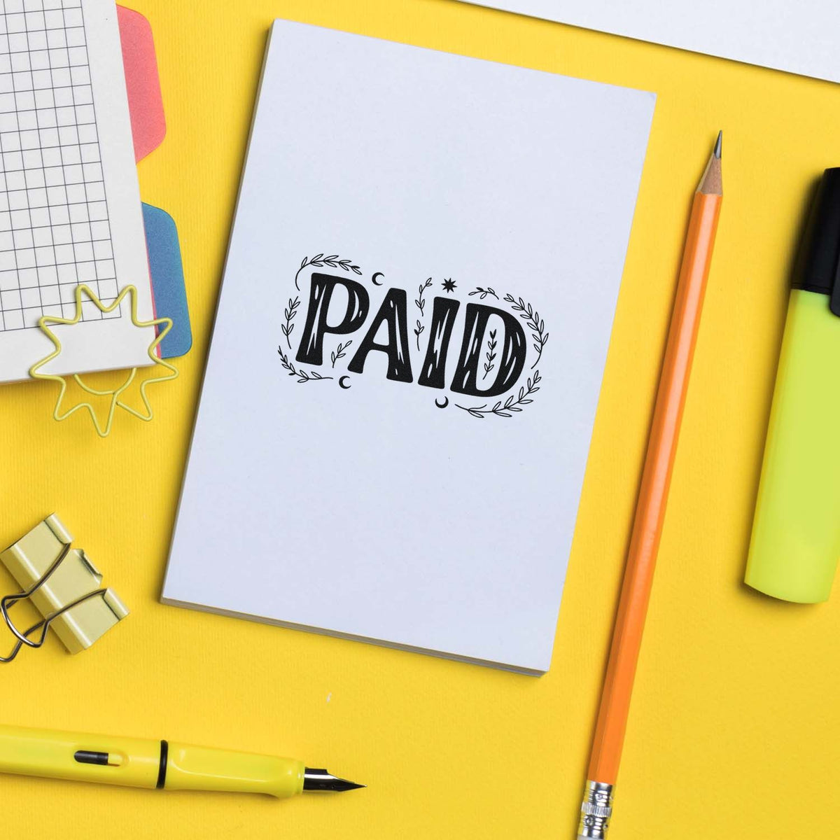 PAID rubber stamp impression on notebook page with stationery, ideal for office accounting and business document marking.