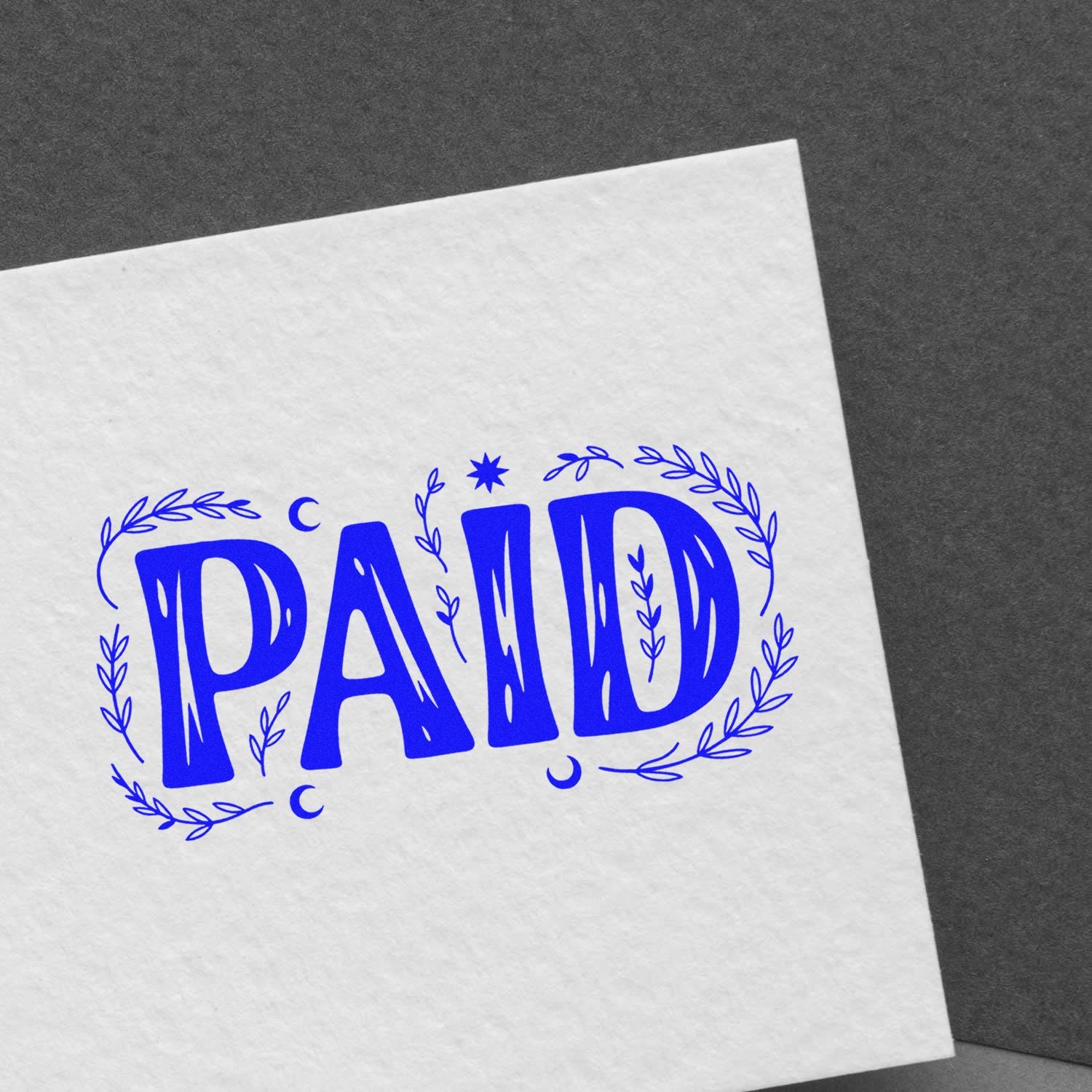 Blue PAID rubber stamp impression with decorative wreath on white paper, ideal for accounting and invoice approval.