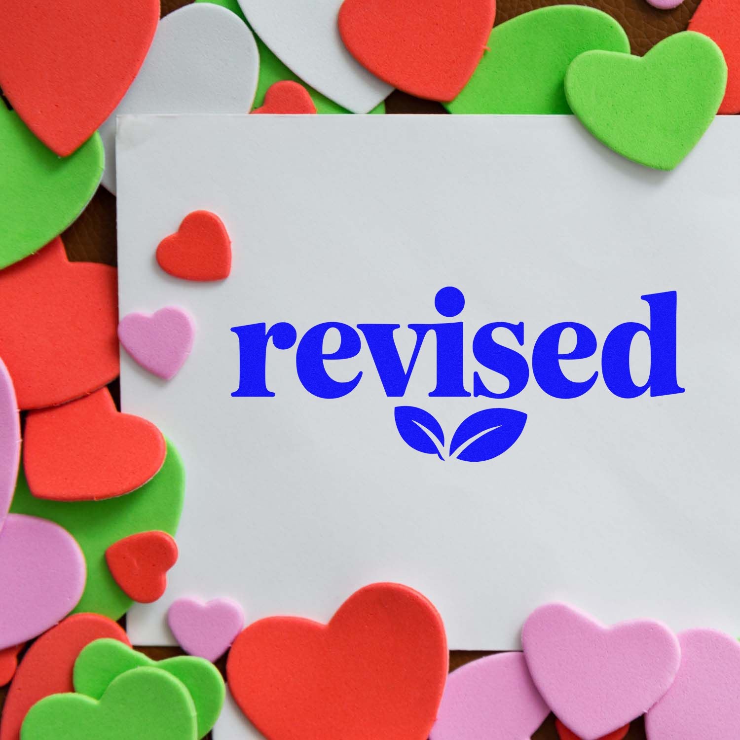 Revised rubber stamp on white paper, framed by colorful heart cutouts for office, school, or craft use.