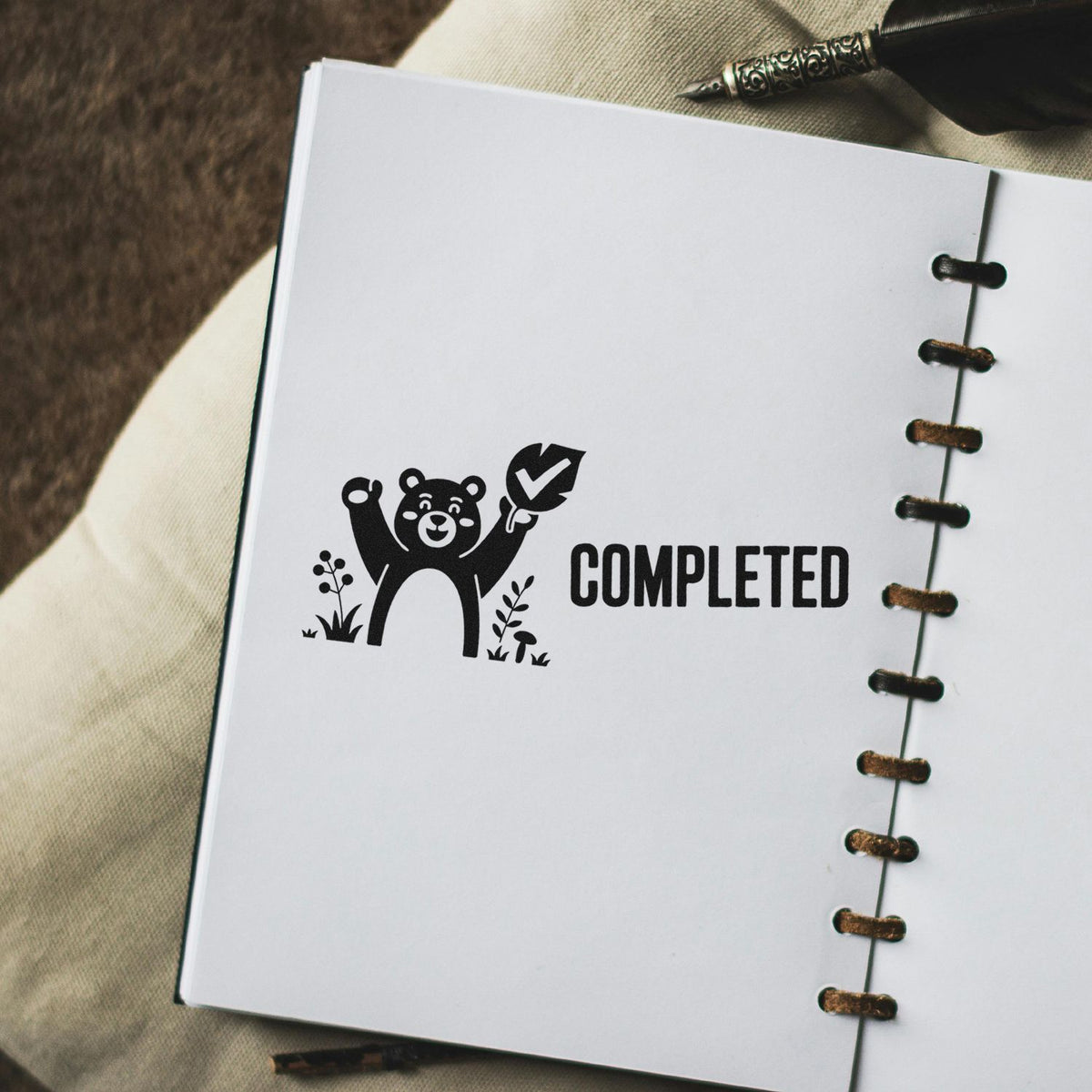 Custom rubber stamp with bear and checkmark design marking a planner page as completed.