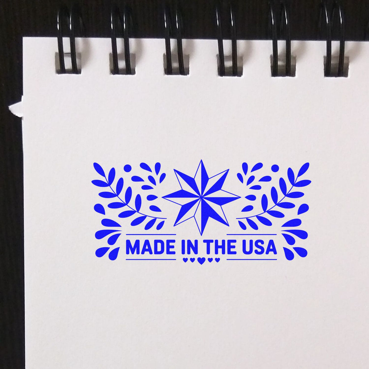 Made in the USA rubber stamp impression with star and leaf wreath for patriotic product branding and packaging.