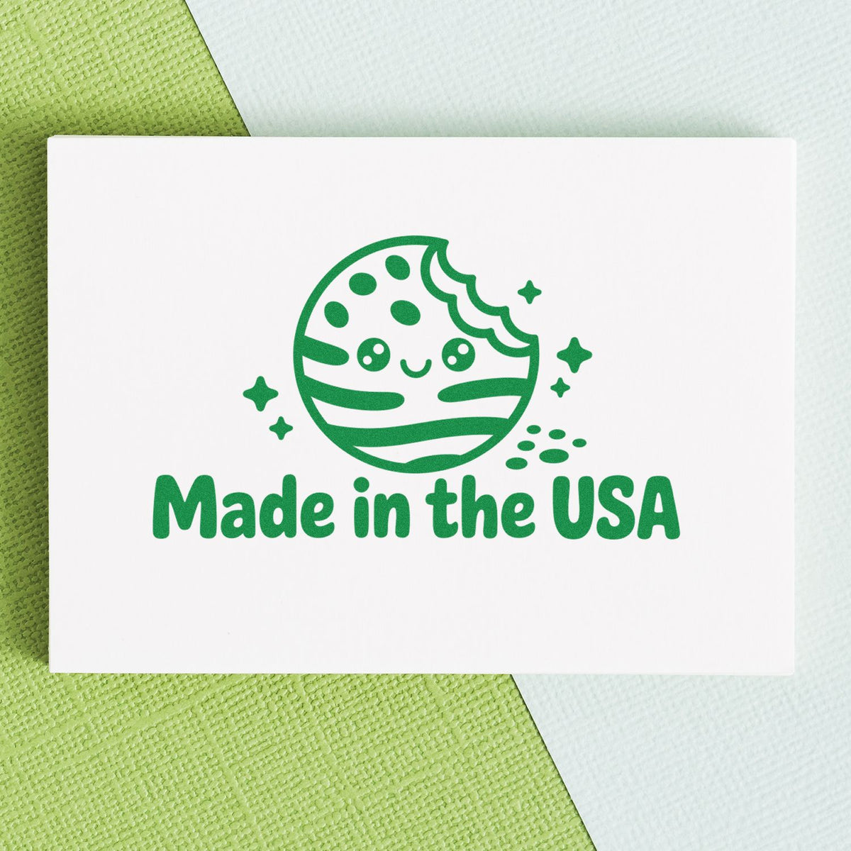 Made in the USA rubber stamp impression with a playful green planet logo on white cardstock.