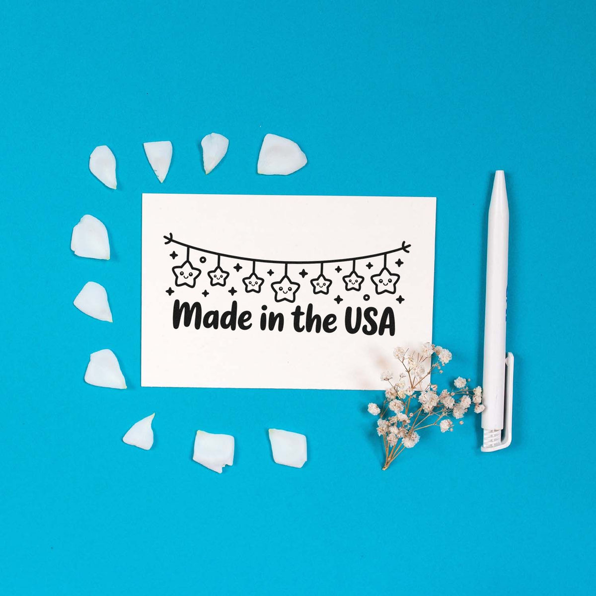 Made in the USA rubber stamp design with hanging stars, displayed on a white card with pen and floral accents.
