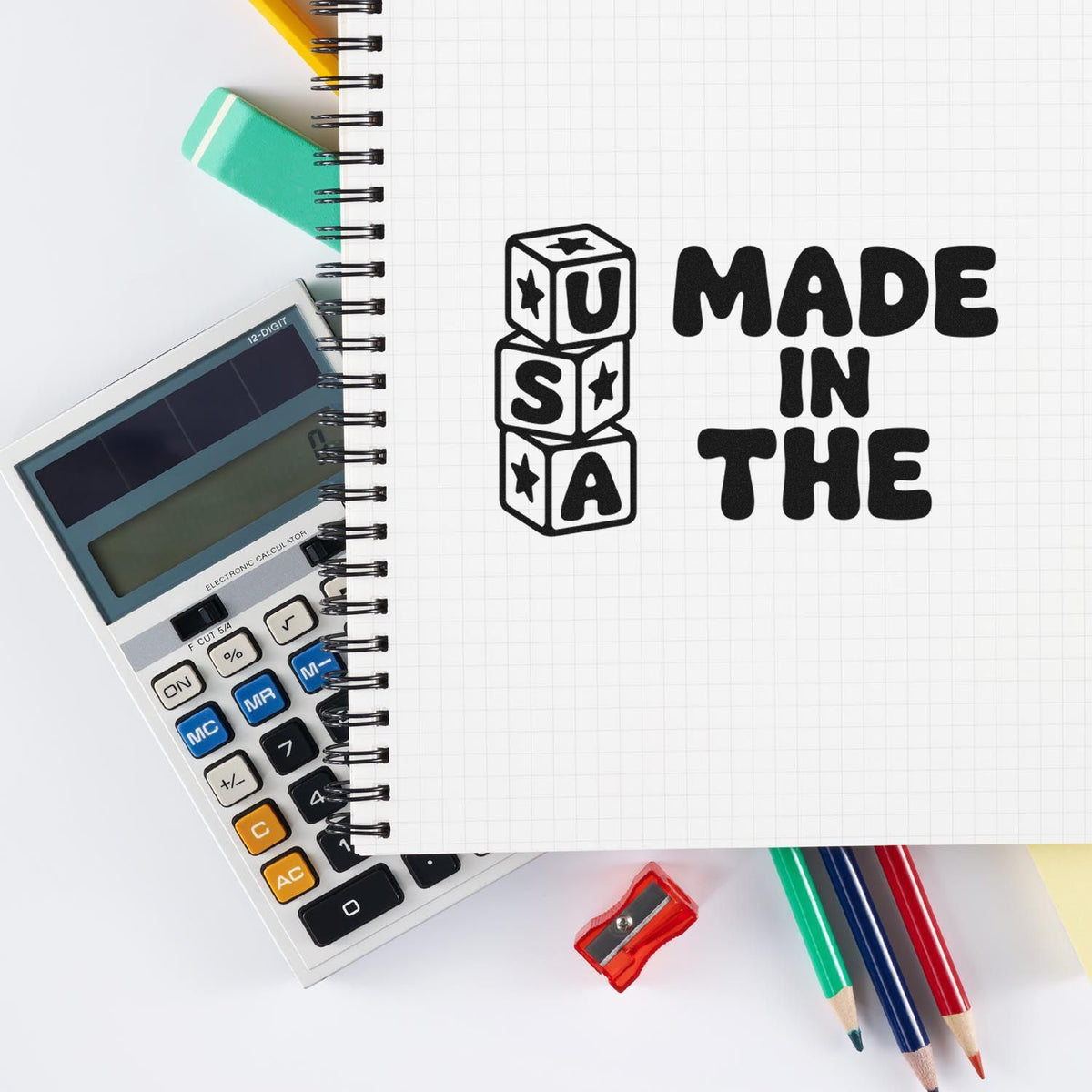 Made in USA rubber stamp design on notebook page with office supplies, calculator, pencils and sharpener.