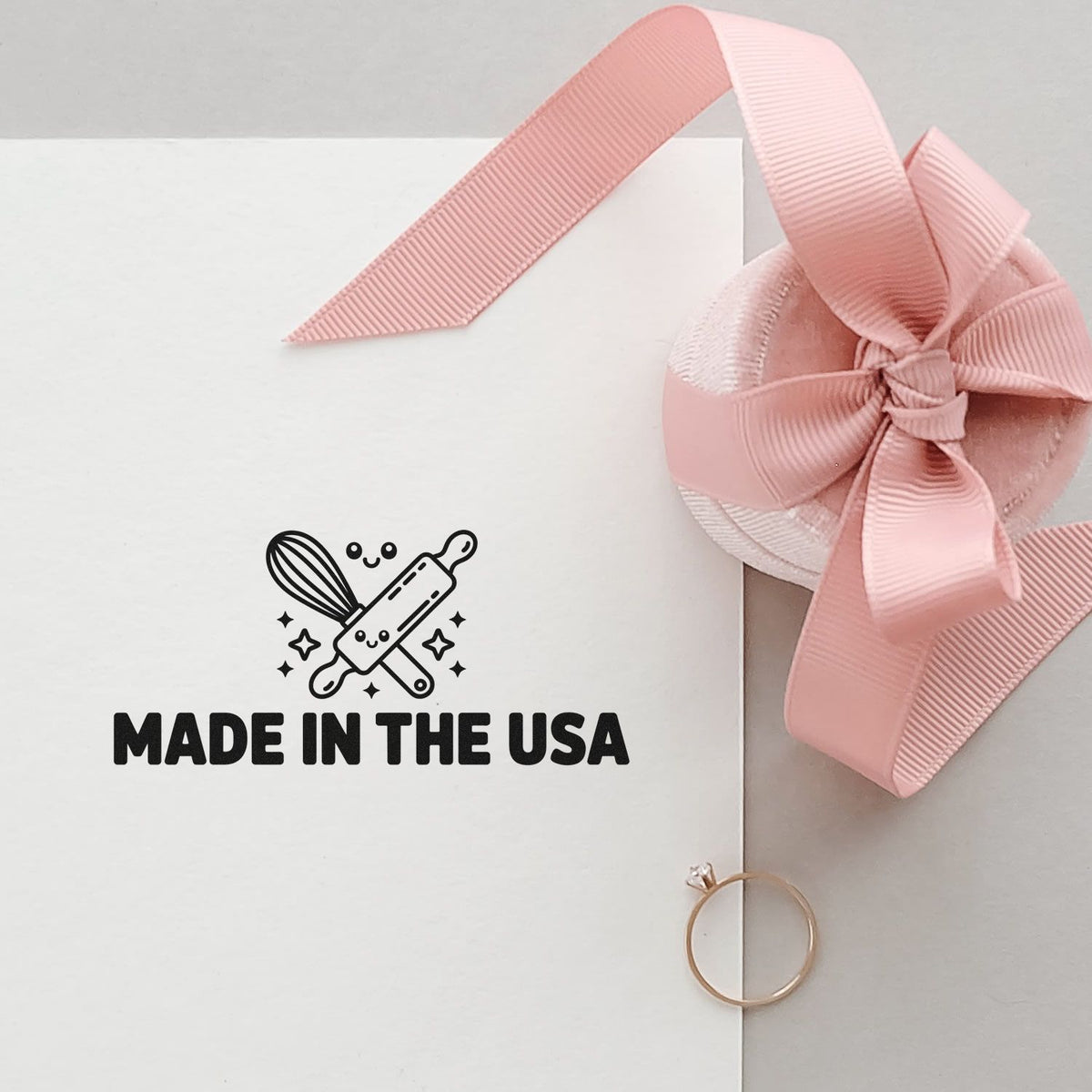 Made in the USA rubber stamp design on a gift box with pink ribbon, perfect for handmade product packaging and branding.