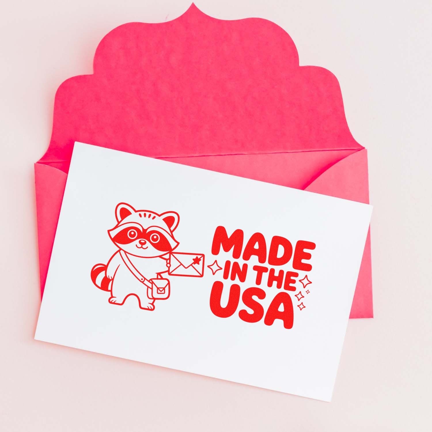Custom rubber stamp design with raccoon and Made in the USA text on a greeting card in a pink envelope.
