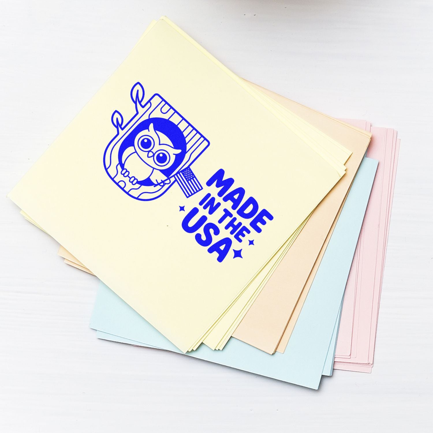 Made in USA owl rubber stamp on pastel paper stack for custom branding and packaging.