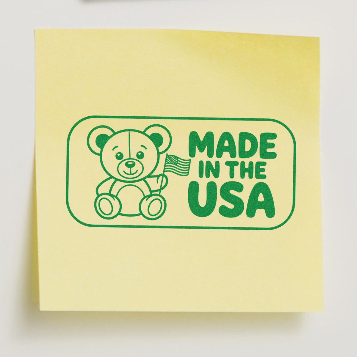 Made in the USA rubber stamp design with teddy bear and American flag, printed in green on a yellow sticky note.