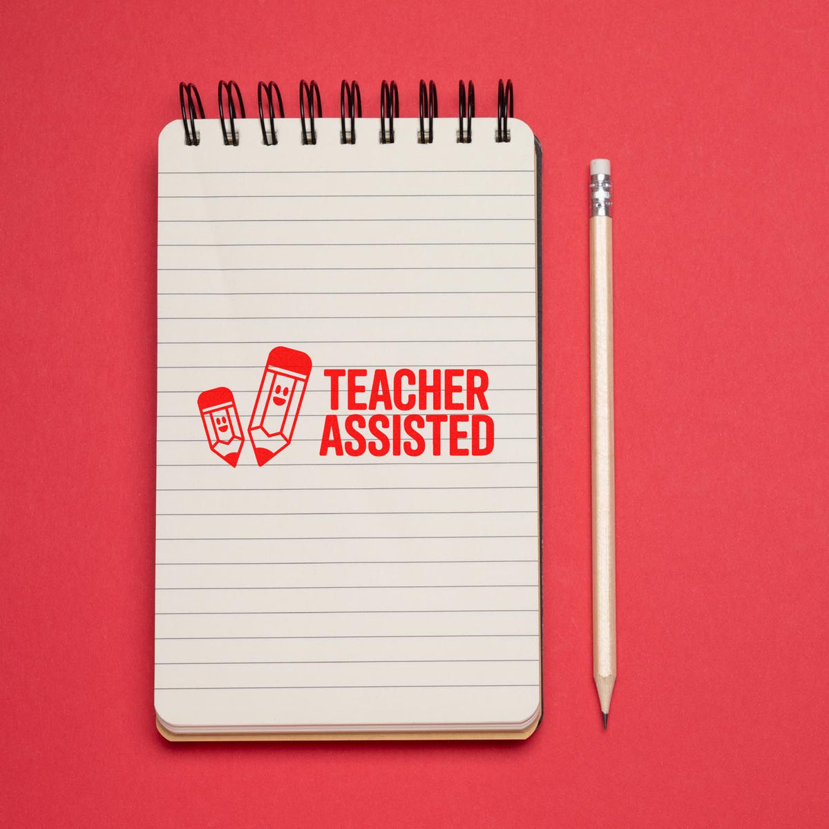 Teacher Assisted rubber stamp on a lined notebook beside a pencil, perfect for classroom grading and teacher feedback.