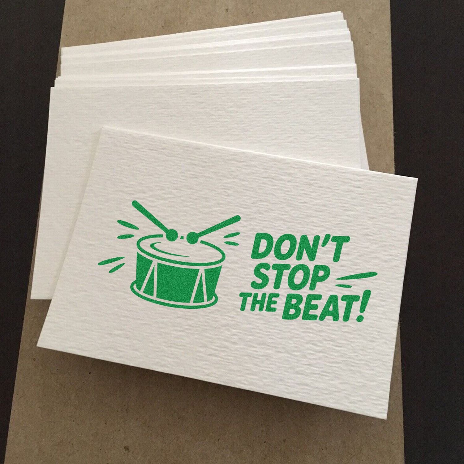 Custom rubber stamp design featuring a drum and Dont Stop the Beat! slogan printed in green on napkins.