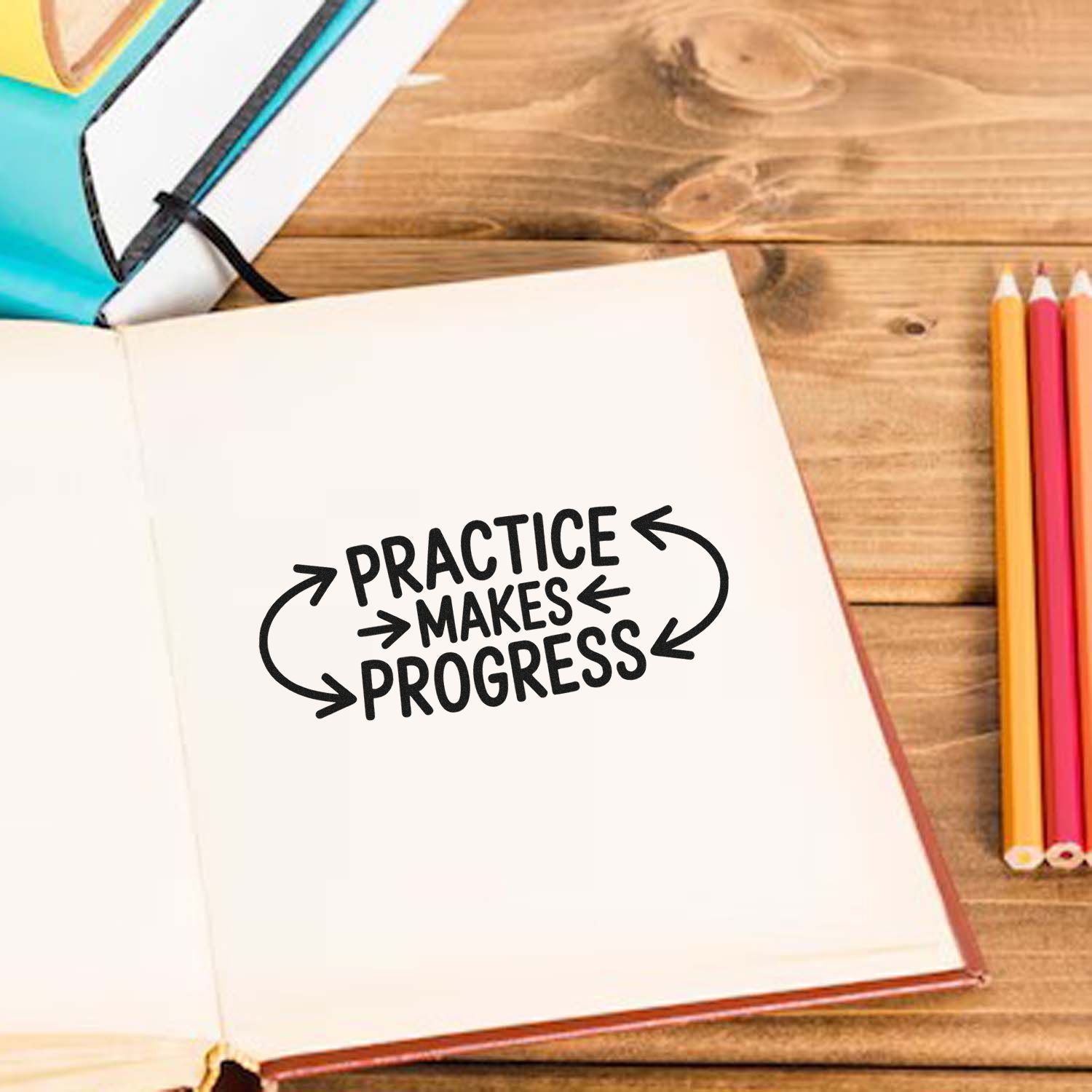 Practice Makes Progress rubber stamp on an open notebook, with pencils on a wooden desk, for motivational school and craft projects