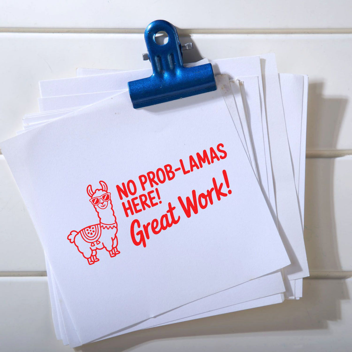 Custom rubber stamp on papers reading No Prob-llamas Here! Great Work! with llama design, ideal for office feedback and rewards.