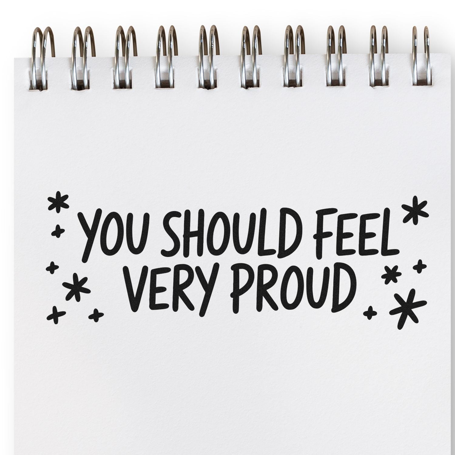 Motivational rubber stamp design with You Should Feel Very Proud in bold hand-lettered text on a spiral notebook page.