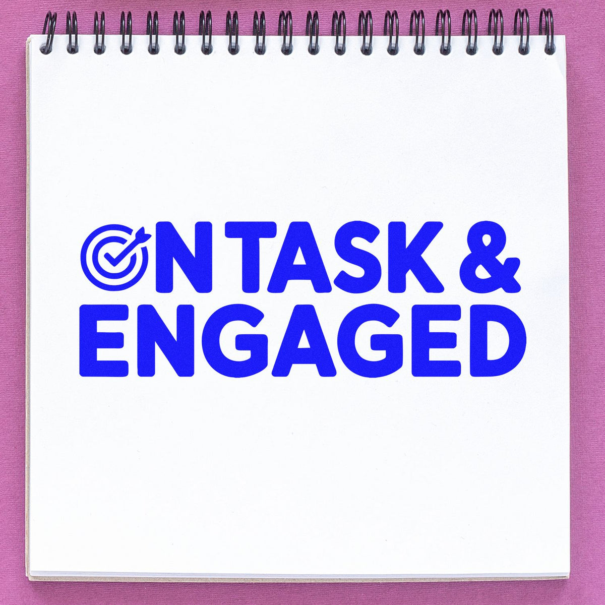 On Task & Engaged rubber stamp imprint in blue on notebook page, with target check icon for classroom feedback.