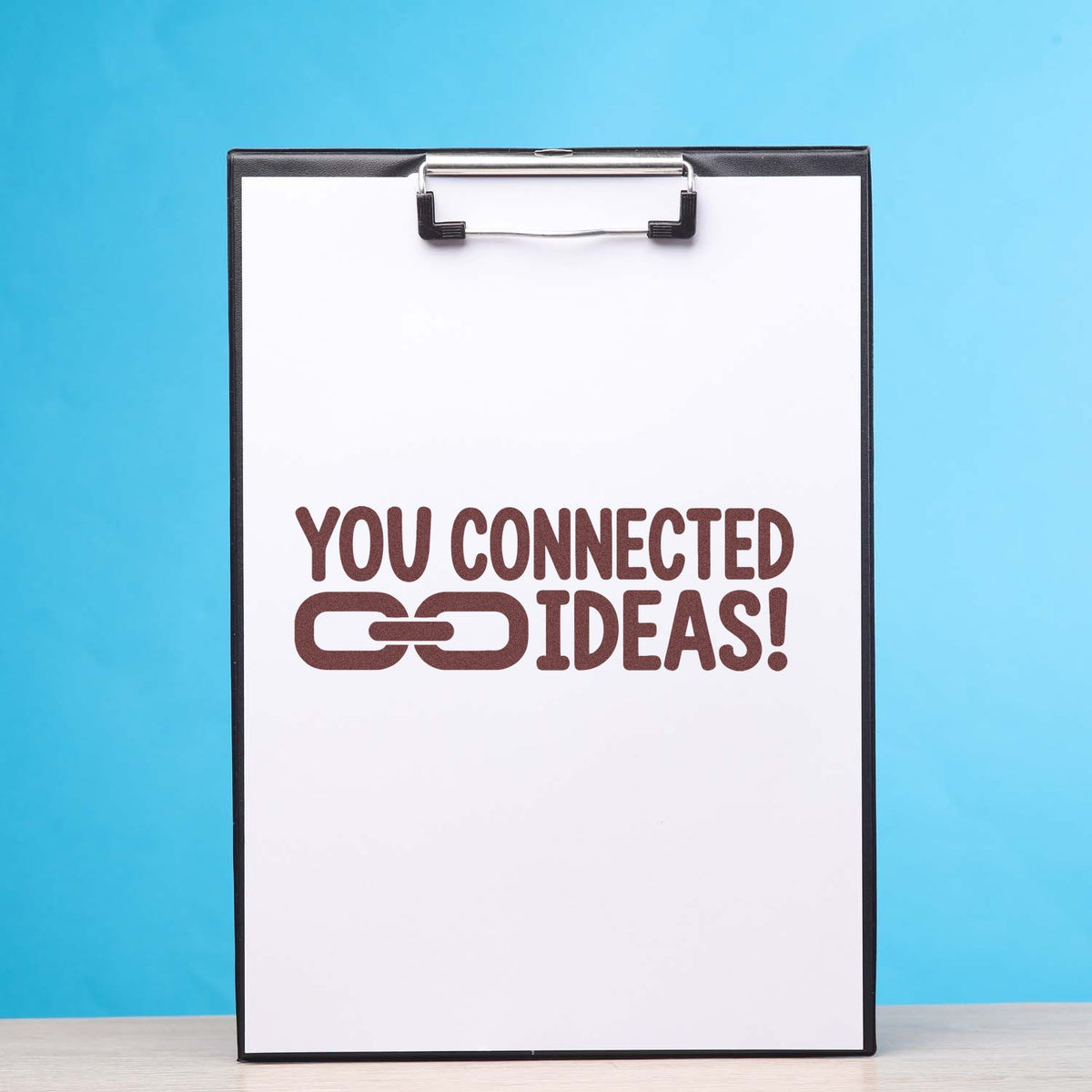 Clipboard with custom rubber stamp impression reading You Connected Ideas! for creative branding and office projects.