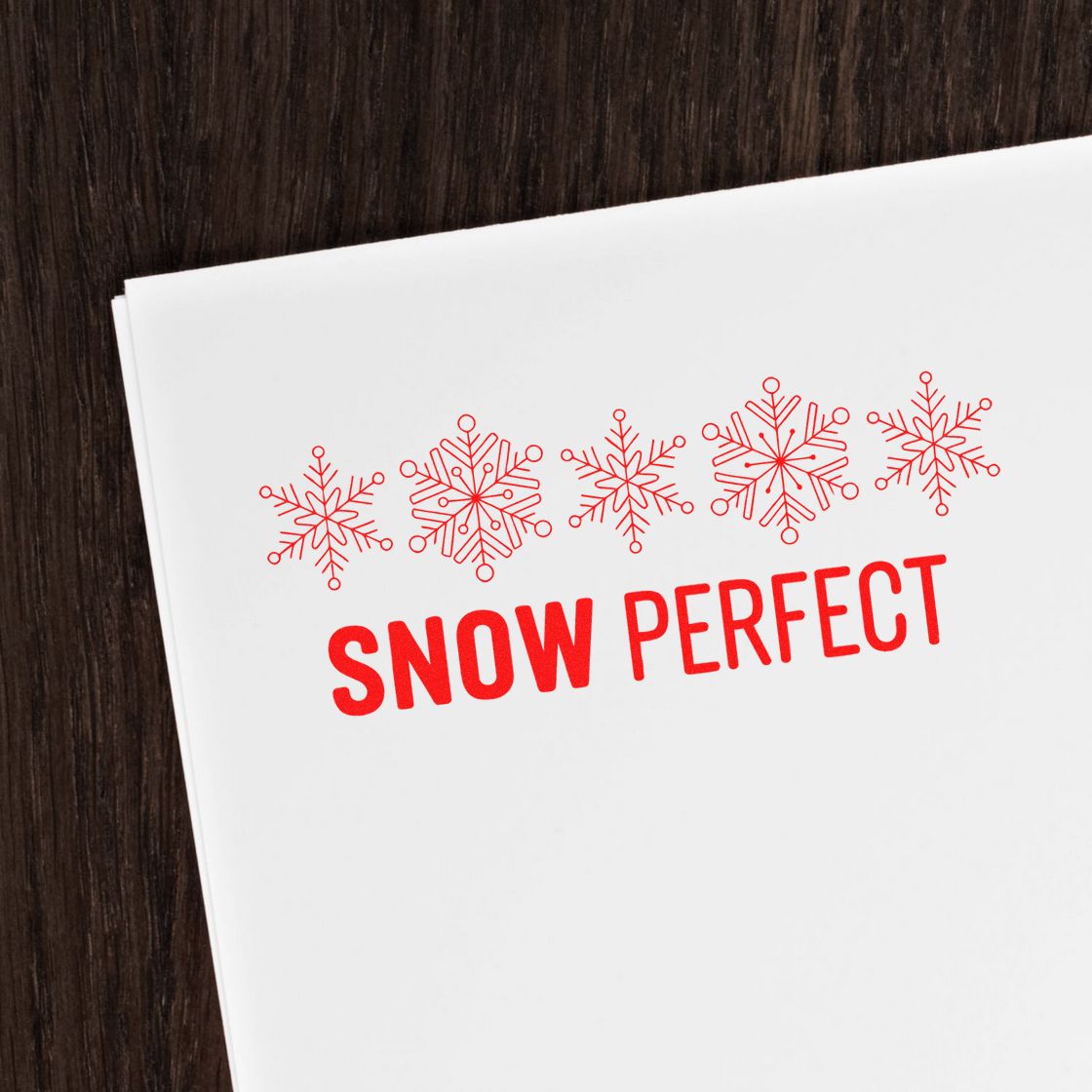 Snow Perfect holiday rubber stamp with red snowflakes on white paper for winter cards and packaging.