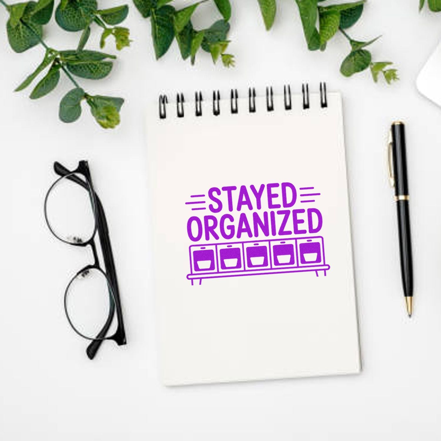 Purple Stayed Organized rubber stamp on notebook with glasses and pen, perfect for planner and office organization.
