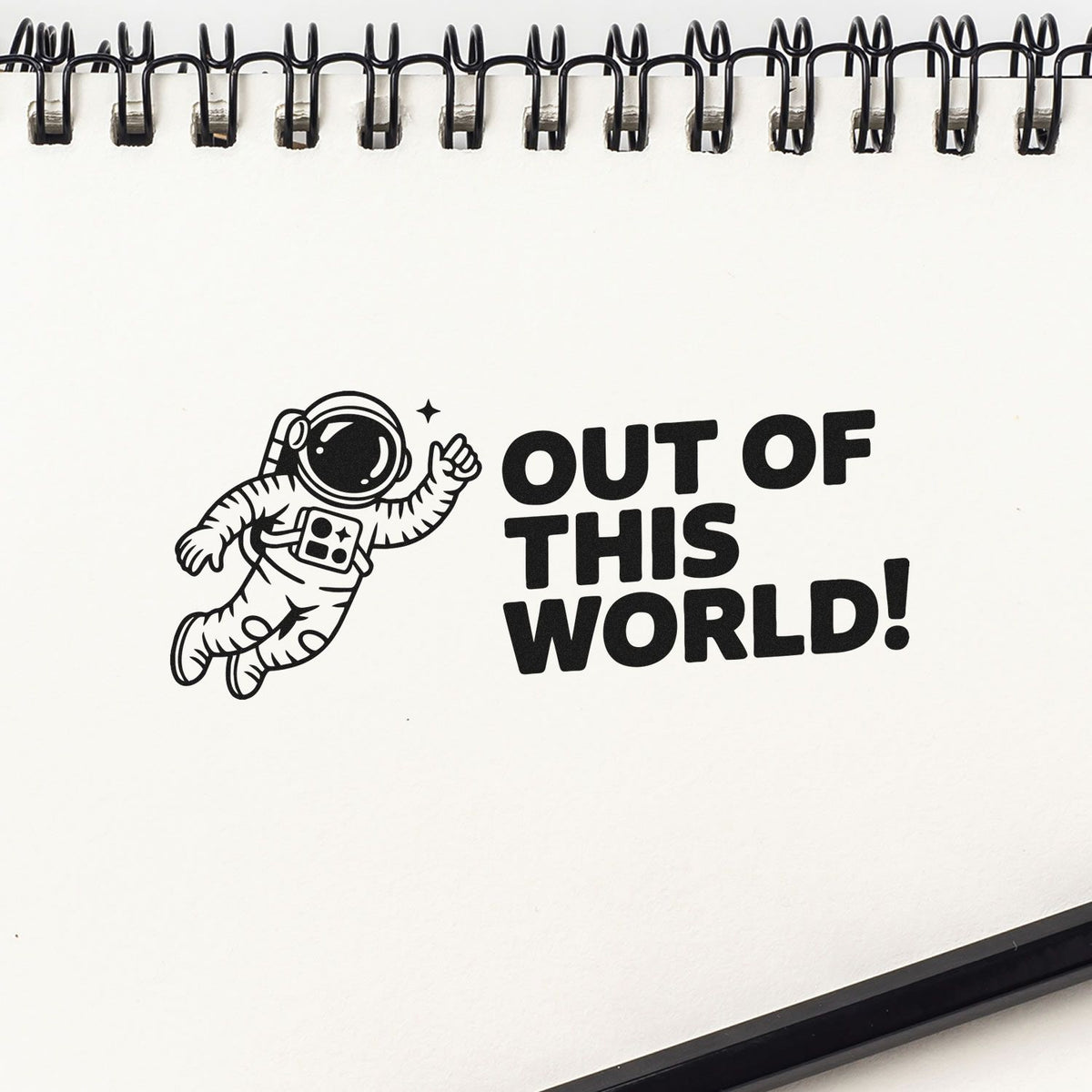 Space-themed rubber stamp design with astronaut and Out of This World! text in a notebook.