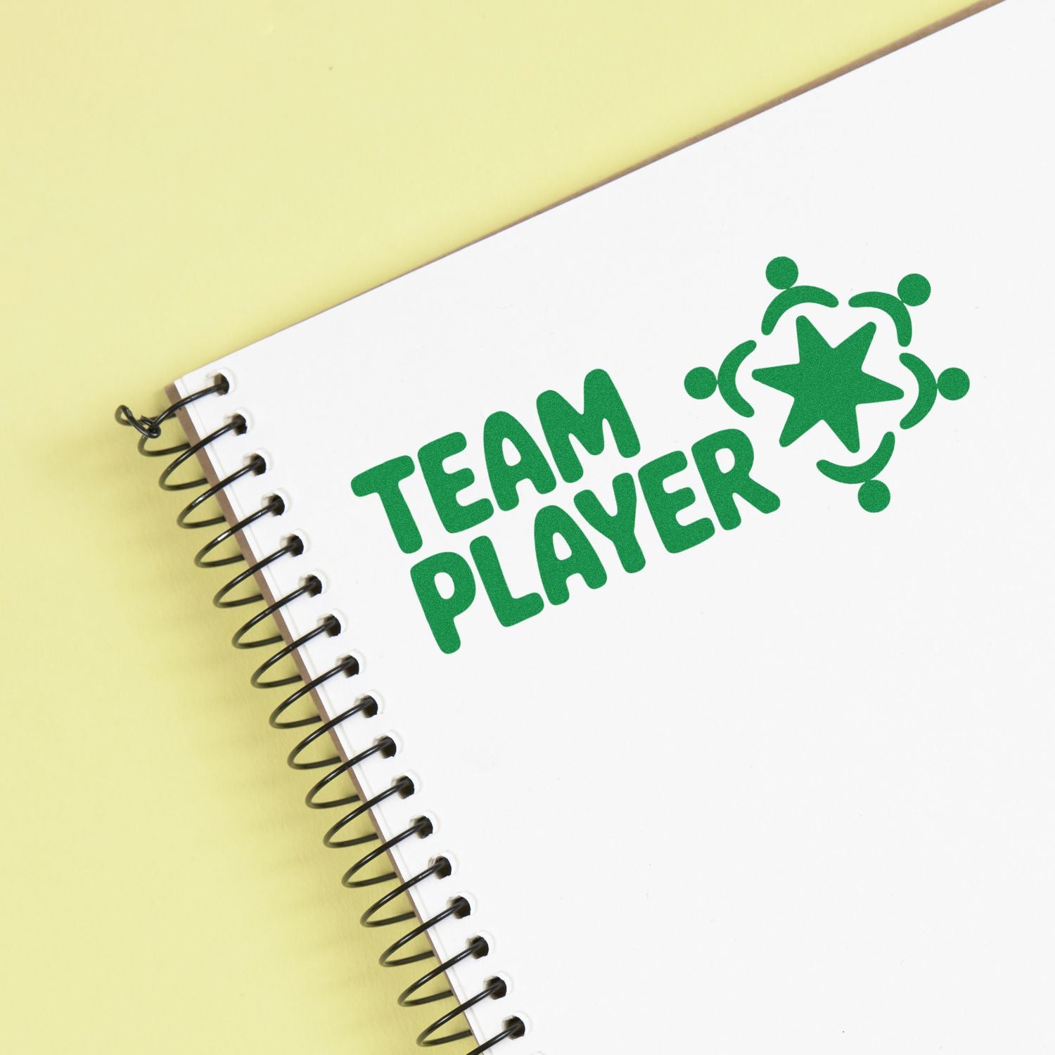 Green Team Player rubber stamp impression on spiral notebook, ideal for teamwork and office recognition.