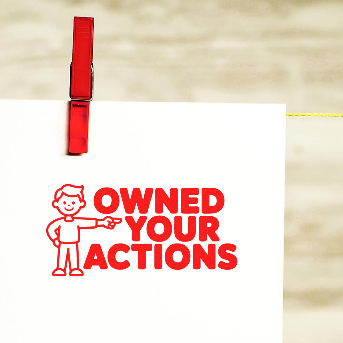 Red rubber stamp imprint reading Owned Your Actions on white paper with a cartoon figure pointing.
