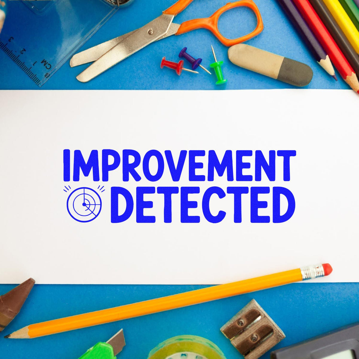 Improvement Detected rubber stamp on paper surrounded by school supplies, ideal for teacher feedback and office use.