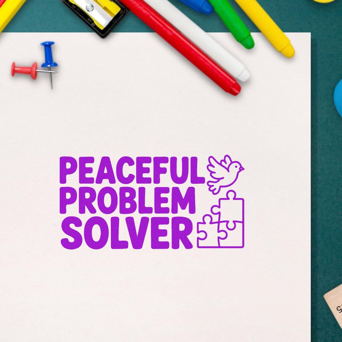 Purple rubber stamp design reading Peaceful Problem Solver with dove and puzzle pieces on paper, surrounded by school supplies.