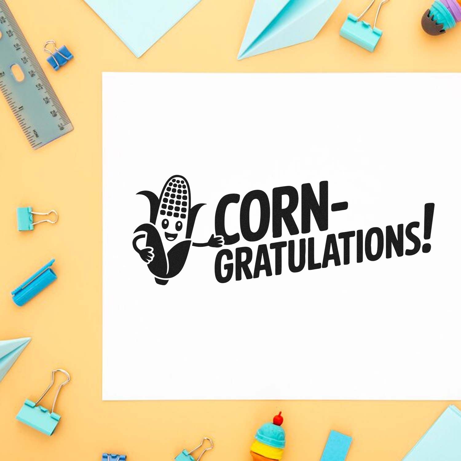Corn-gratulations rubber stamp design with smiling corn cob for congratulation cards, classroom crafts, and fall-themed stamping projects.
