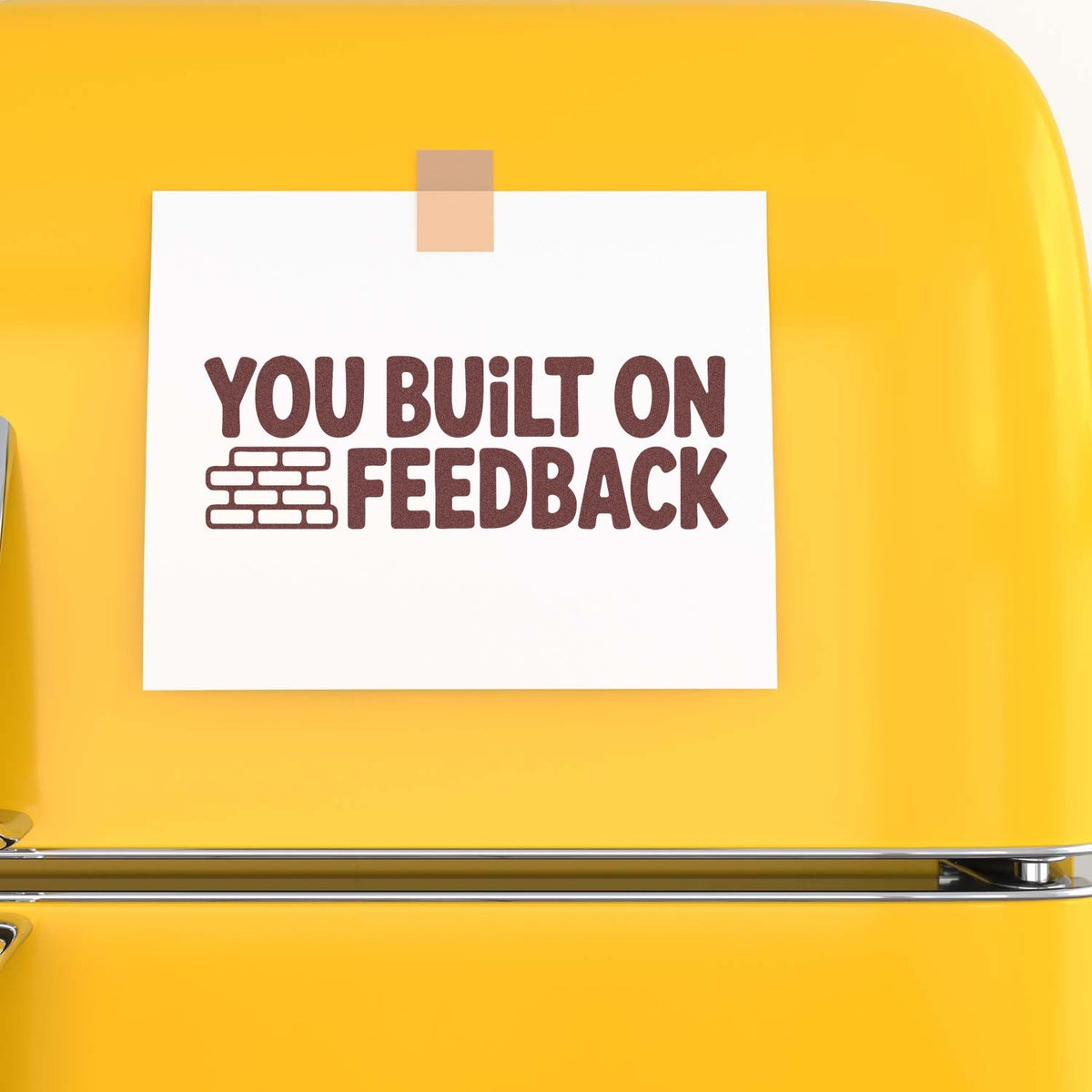Rubber stamp reading You Built on Feedback with brick icon, shown on a yellow background.