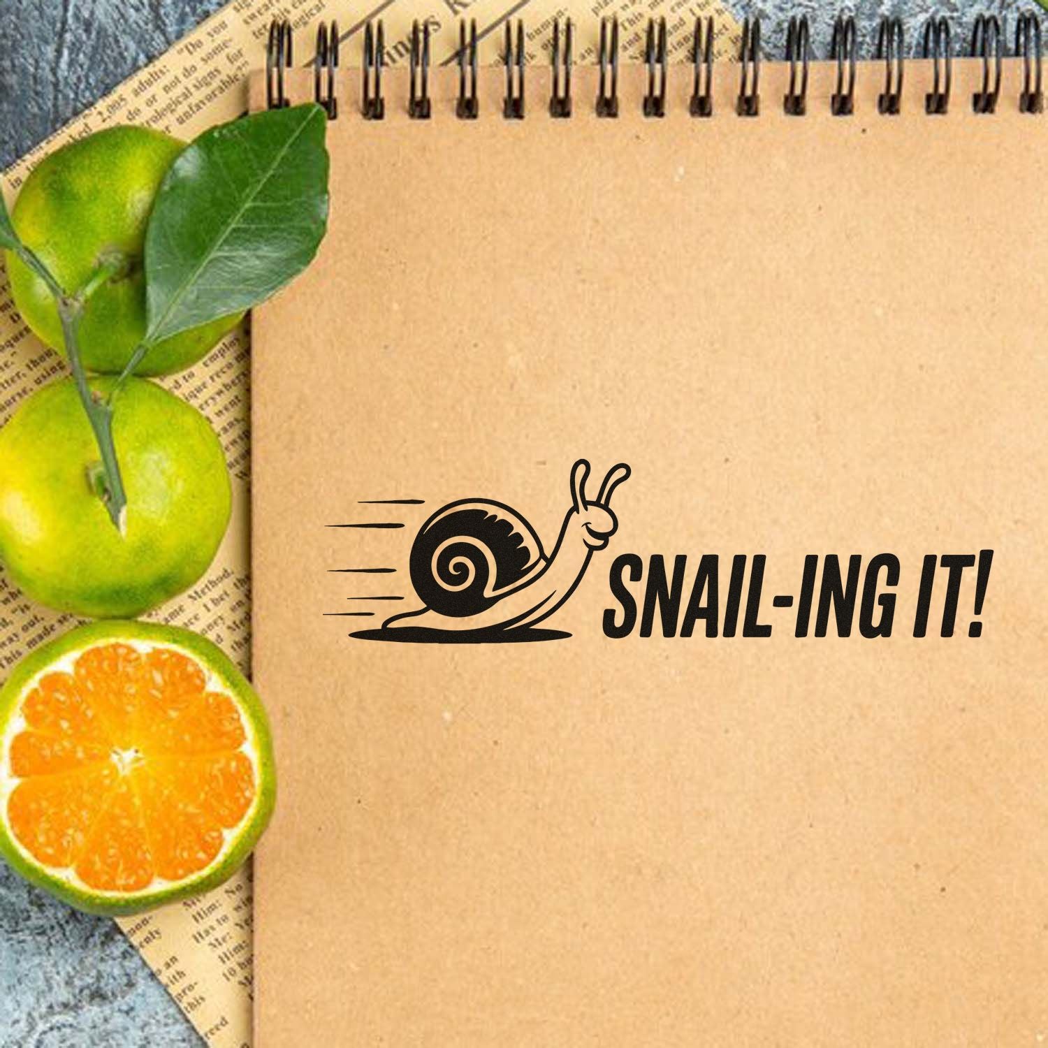 Snail-ing It! rubber stamp design with a playful snail graphic on kraft paper notebook for journaling, planners and crafts.
