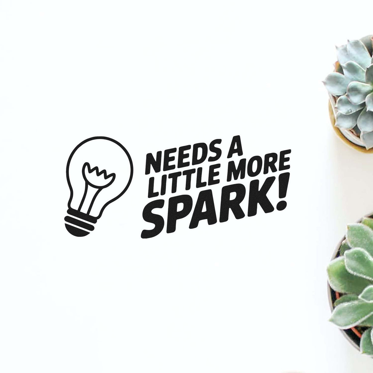 Funny custom rubber stamp design with lightbulb icon and Needs a little more spark! quote for motivational crafts and office use.
