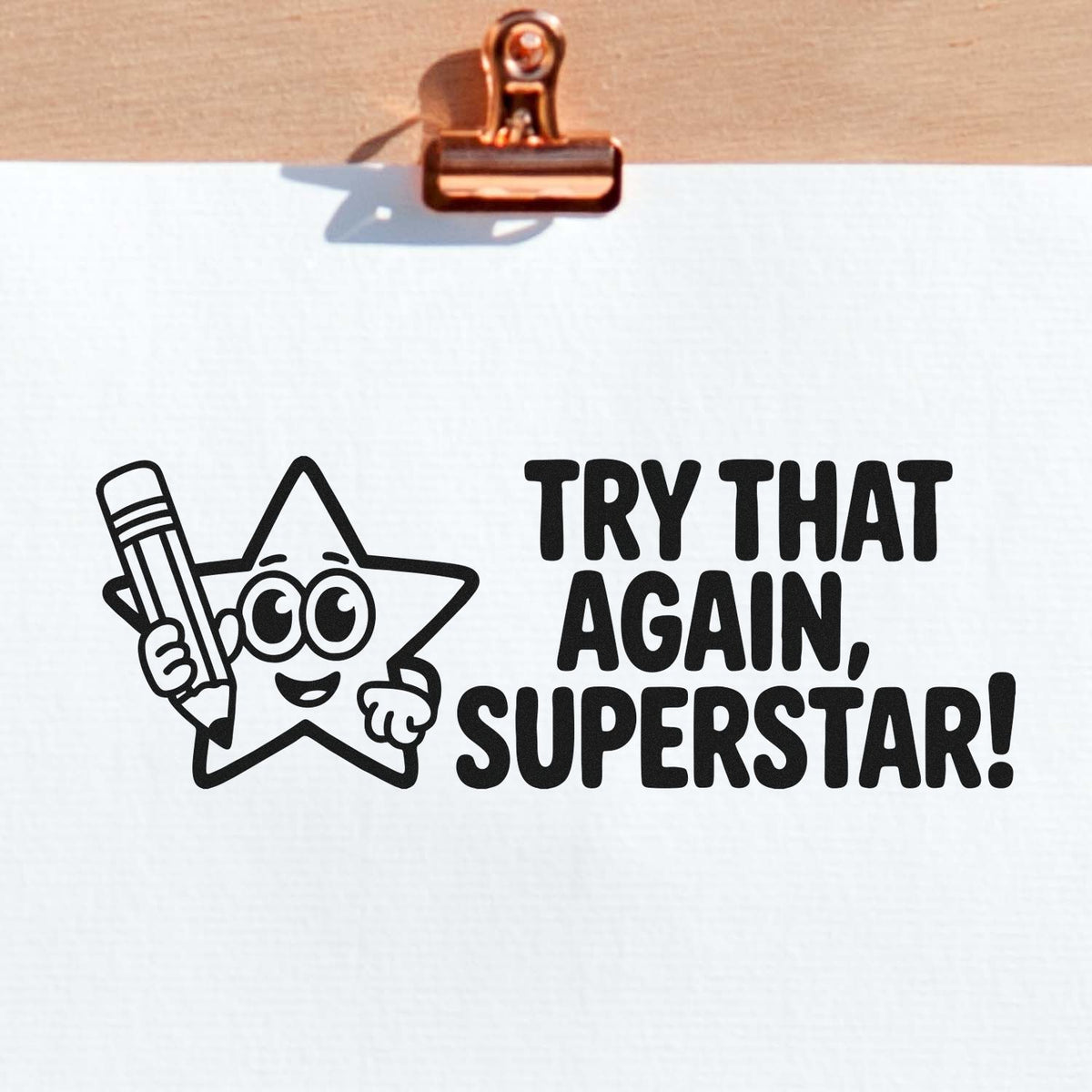 Rubber stamp design with Try That Again, Superstar! text and star holding a pencil on paper.