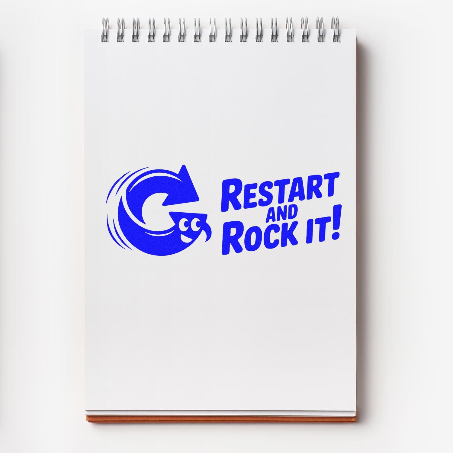 Motivational rubber stamp on notebook with blue Restart and Rock It! text and circular arrow logo