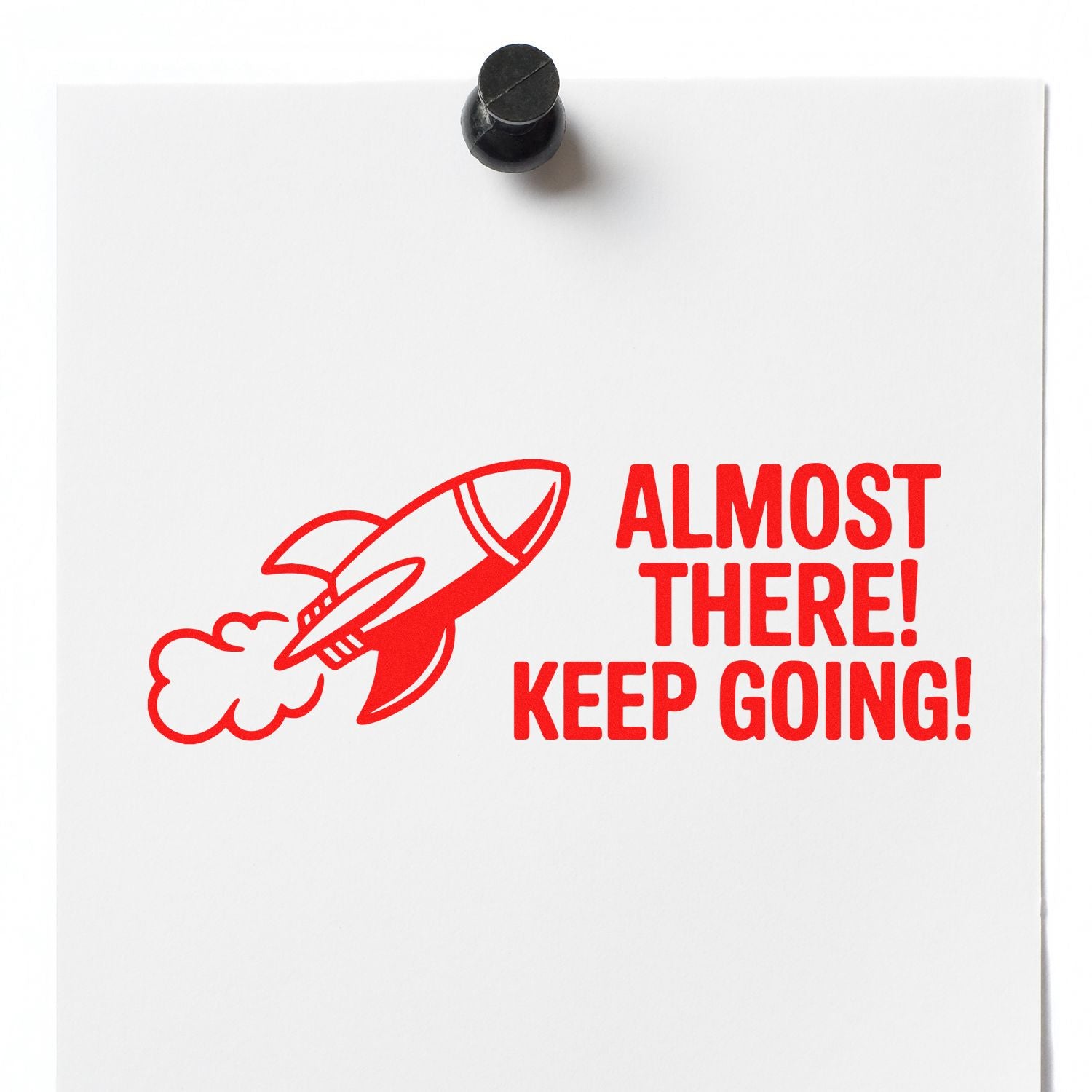 Motivational rubber stamp design with rocket and Almost There! Keep Going! message on white paper.