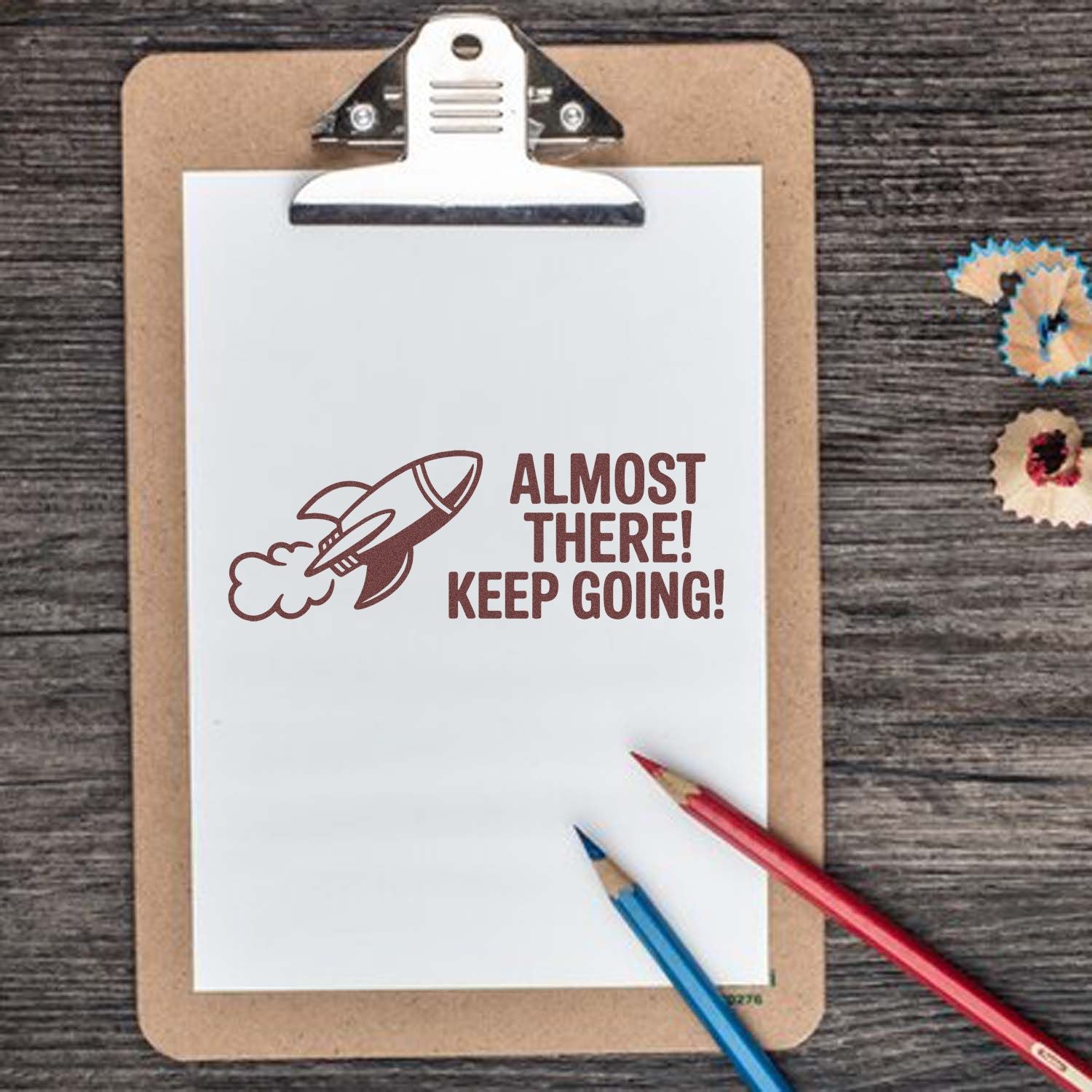 Motivational rocket rubber stamp design with Almost There! Keep Going! on clipboard for planner and craft projects.