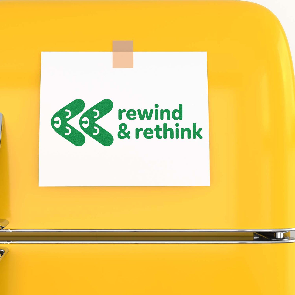 Custom rubber stamp design with green rewind & rethink logo on paper, shown on a yellow fridge for sustainable branding.