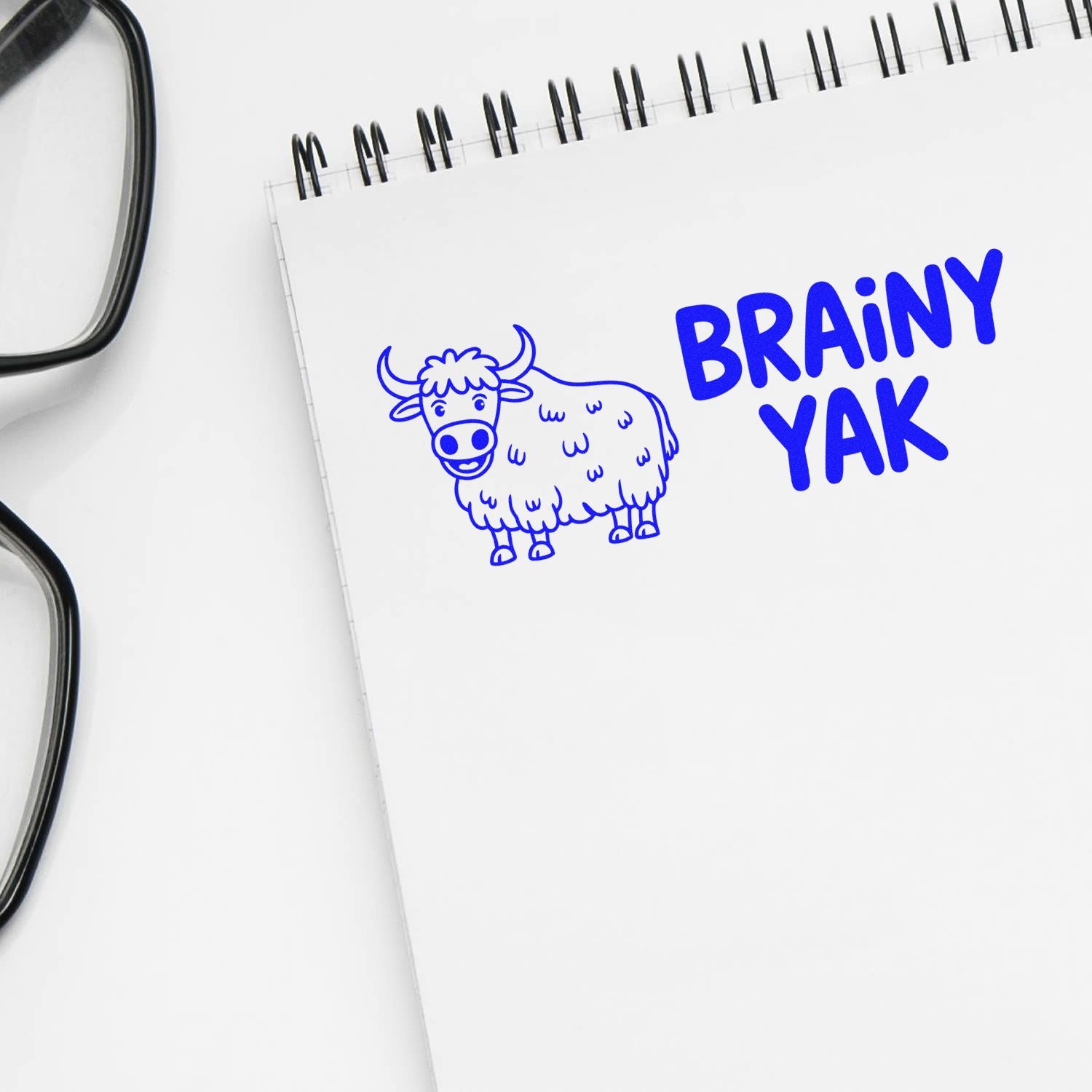 Brainy Yak custom rubber stamp design with blue yak illustration on notebook for branding.