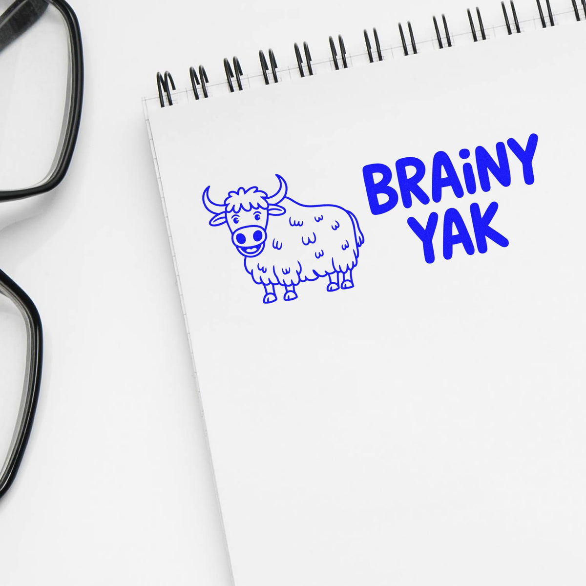 Brainy Yak custom rubber stamp design with cartoon yak logo on notebook, ideal for fun office branding and packaging.