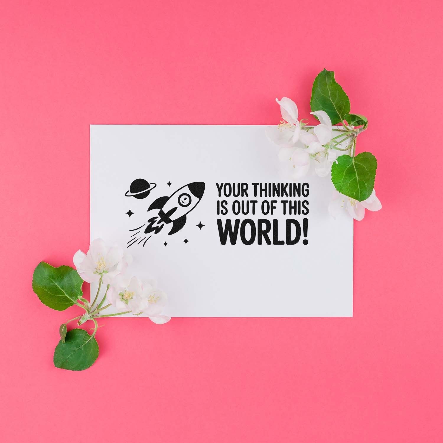 Rubber stamp design with rocket and Your thinking is out of this world! message on white card with flowers on pink background.