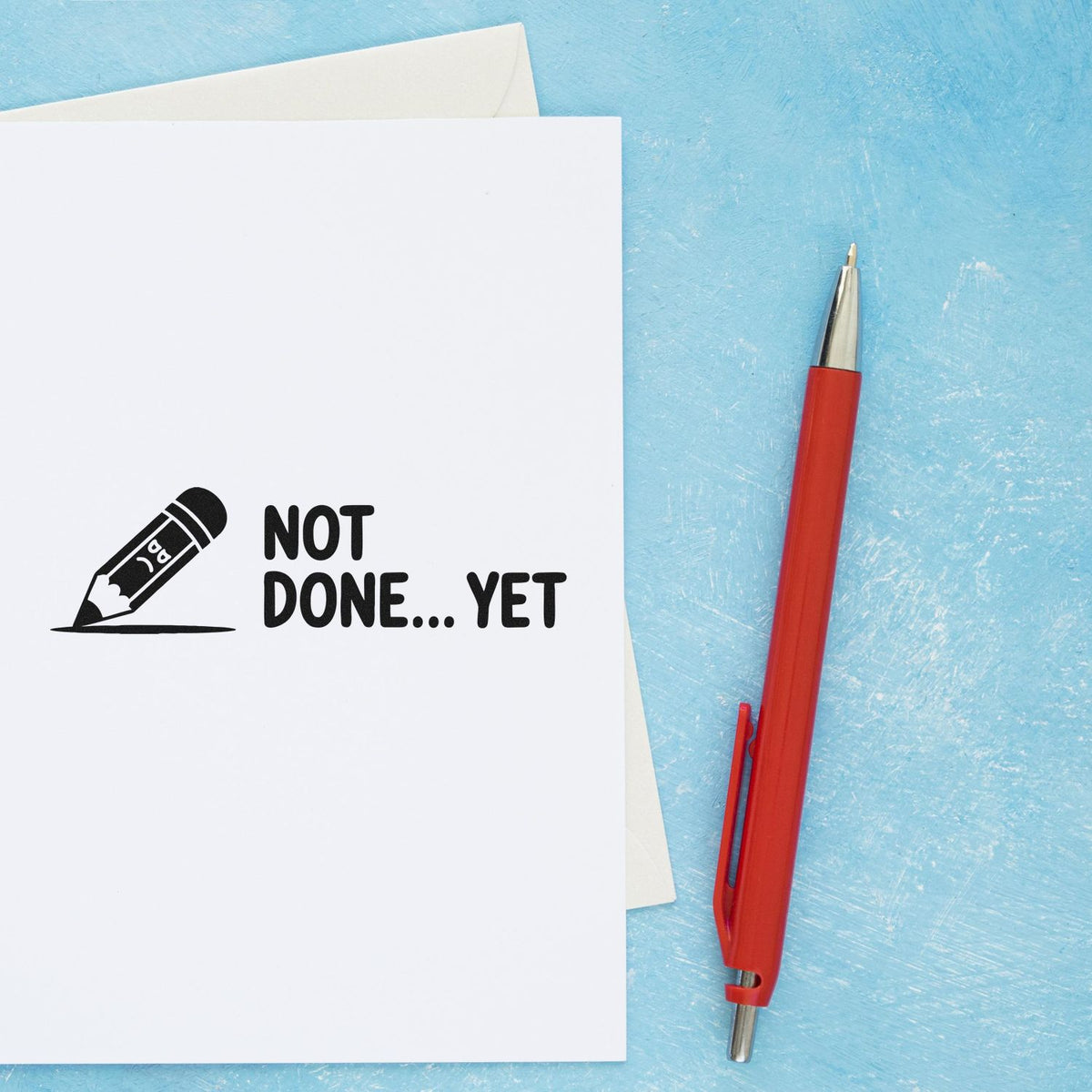 Not Done... Yet rubber stamp design on paper with pencil icon, shown beside a red pen on a blue background.